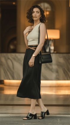 Woman with short curly hair wearing a crop top and black skirt indoors