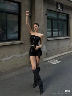Woman in a black tube top and shorts with boots on a street