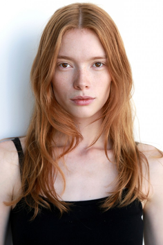 Woman with long red hair and freckles wearing a black top