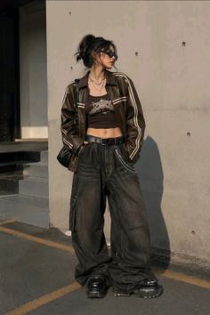 Person in a brown leather jacket and baggy jeans standing outdoors