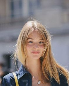 Young woman with blonde hair and freckles wearing a denim jacket and necklace
