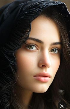 Close up portrait of a woman with green eyes and dark hair, wearing a dark hood