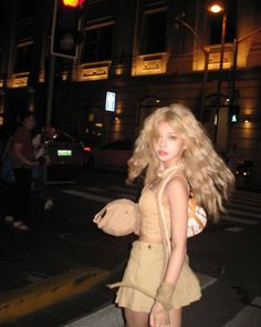 Blonde woman in a crop top and mini skirt on a city street at night