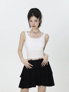 Woman in a white crop top and black tiered skirt posing in a studio