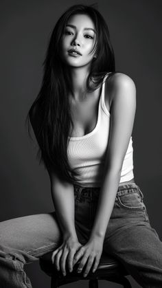 Woman in a white tank top and jeans sitting in a studio, black and white photo
