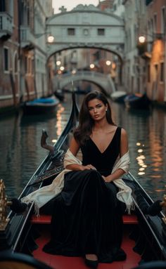 Woman in a black dress and shawl sitting in a gondola on a Venice canal