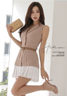 Woman in a pinstripe top and pleated skirt holding a clutch bag