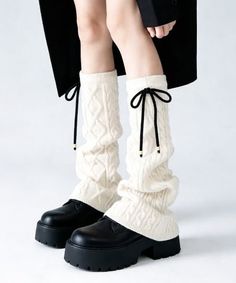 Person wearing cream cable knit leg warmers and chunky black platform shoes