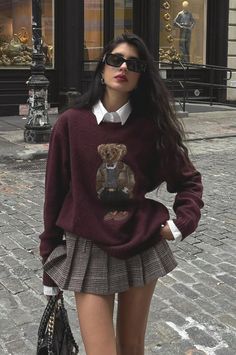 Woman in a teddy bear sweater and plaid skirt on a cobblestone street
