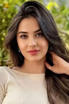Woman with long brown hair and earrings in a soft-lit outdoor portrait