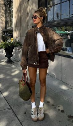 Woman in a brown jacket and mini skirt on a sunny street