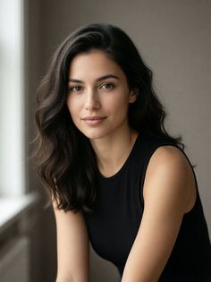 Woman with long wavy hair wearing a black top, looking at the camera