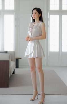 Woman in a satin top and mini skirt standing indoors