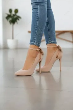 Person wearing blue jeans and nude high heels with ankle straps and bows