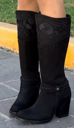 Pair of black boots with embroidered floral details and braided straps