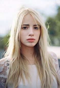 Woman with long blonde hair wearing a lace top outdoors