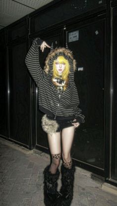 Person with blonde hair in a striped hoodie and furry boots at night