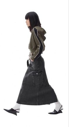 Woman in a cropped hoodie and long denim skirt walking in profile