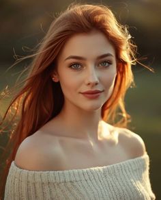 Woman with long red hair and blue eyes in an off-shoulder sweater at golden hour