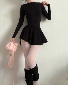 Person in a black leotard and white tights with leg warmers holding pink fabric