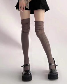 Person wearing a black mini skirt, brown thigh-high socks, and platform mary jane shoes