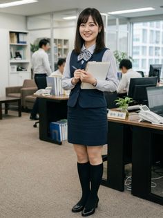 Woman in an office uniform smiling and holding a notebook in an office setting