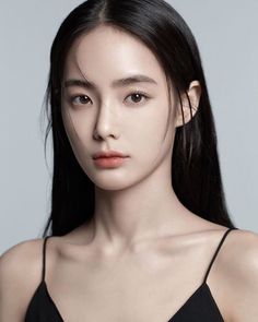 Woman with long black hair wearing a black top, looking directly at the camera