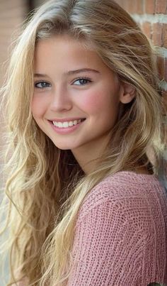 Young girl with blonde hair and a pink sweater smiling at the camera
