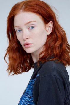 Woman with red hair and blue eyes wearing a dark t-shirt