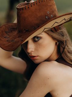 Woman with a cowboy hat covering part of her face, looking over her shoulder