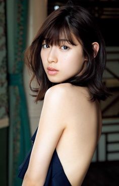 Woman with short dark hair looking over her bare shoulder
