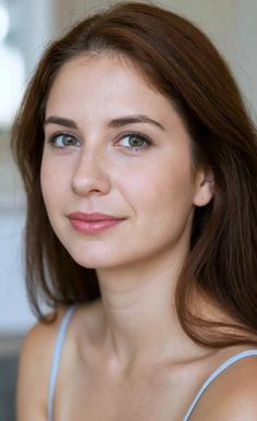 Woman with long brown hair and green eyes wearing a light blue top