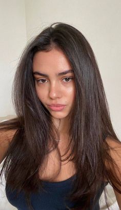 Woman with long dark hair wearing a black tank top, looking directly at the camera