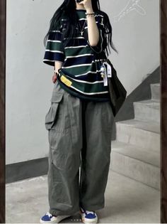 Person in a striped shirt and cargo pants standing indoors