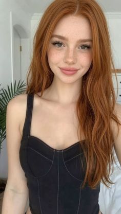 Woman with red hair and freckles wearing a black top indoors