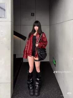 Woman in a red leather jacket and black corset with platform boots indoors