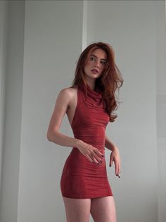 Woman with long red hair in a tight red dress posing indoors