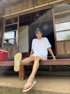 Woman in a white t-shirt and flip flops sitting on a wooden porch