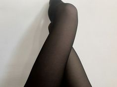 Legs in black tights crossed against a white background
