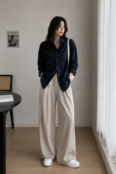 Woman in a navy shirt and wide leg pants standing indoors