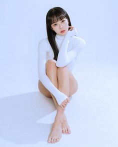 Woman in a white bodysuit sitting on a light background