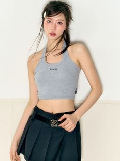 Woman in a gray halter top and black pleated skirt with an exposed midriff
