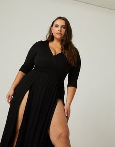 Woman in a black dress with high slits and cleavage in a studio setting