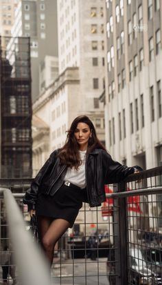 Woman in a black leather jacket and mini skirt posing on a city street