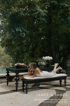 Woman in a white dress relaxing on an outdoor bench next to a dining table