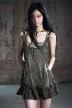 Woman with long dark hair and dark makeup wearing a sheer layered dress indoors