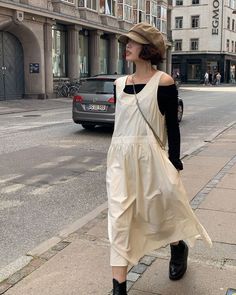 Woman in a beret hat and midi dress walking on a city street