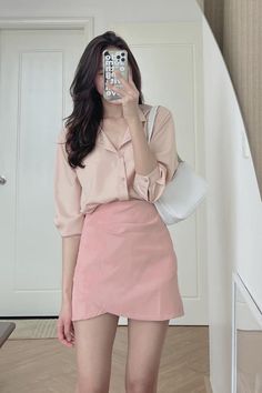 Woman in a pink shirt and skirt taking a mirror selfie