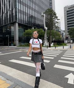 Woman in a crop top and plaid skirt walking on a city street