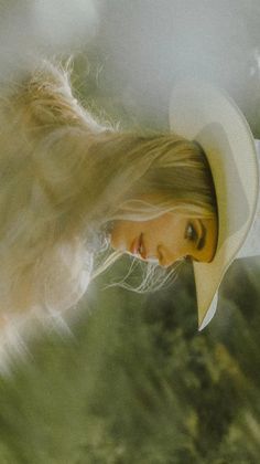 Blonde woman in a cowboy hat with long hair flowing, soft lighting
